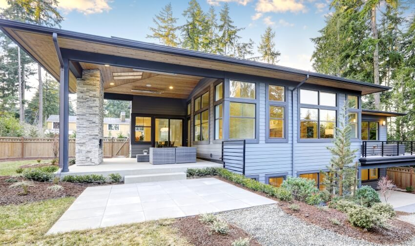 Luxury new home with blue siding and chic patio accented with stone fireplace