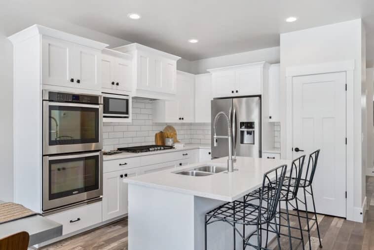 Staggered Kitchen Cabinets Design Tips   Metal Stools Stainless Steel Double Oven And French Door Refrigerator In White Kitchen Is 758x506 