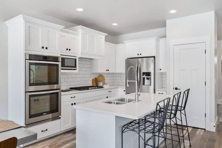 Staggered Kitchen Cabinets Design Tips   Metal Stools Stainless Steel Double Oven And French Door Refrigerator In White Kitchen Is 768x512 