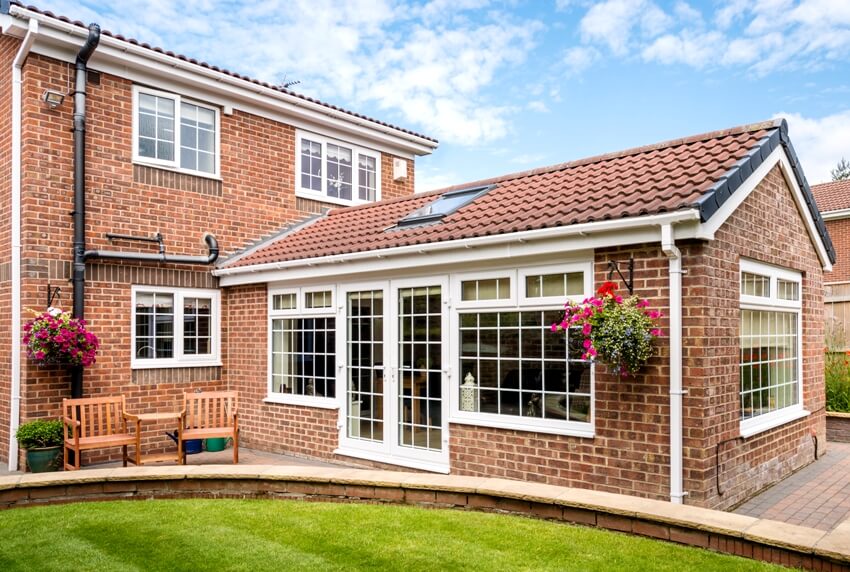 Modern sunroom extending into the garden surrounded by a block paved patio