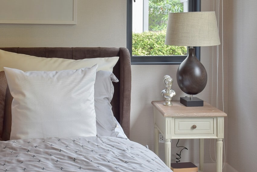 Modern bedroom interior with white and brown pillow on bed and decorative table lamp