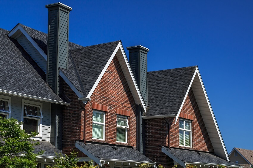 Modern brick residential building with dark roof and chimney