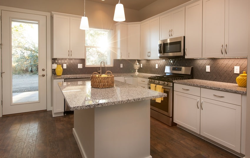 Modern bright kitchen with island dark wood floors grey countertops and white cabinets