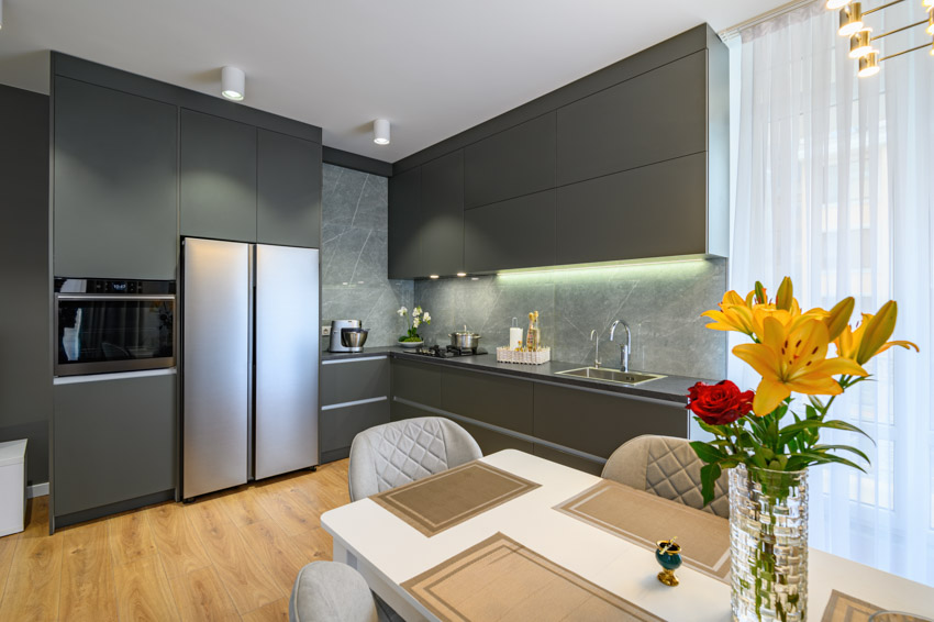 Modern kitchen space with black cabinets windows curtains dining chairs and table backsplash countertop