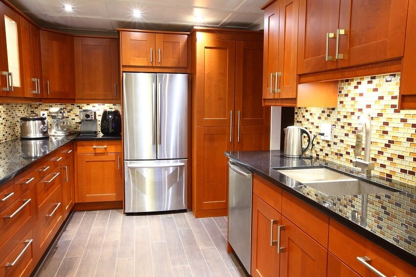 Modern kitchen with varying height upper cabinets, mosaic backsplash, and black galaxy granite counter tops 