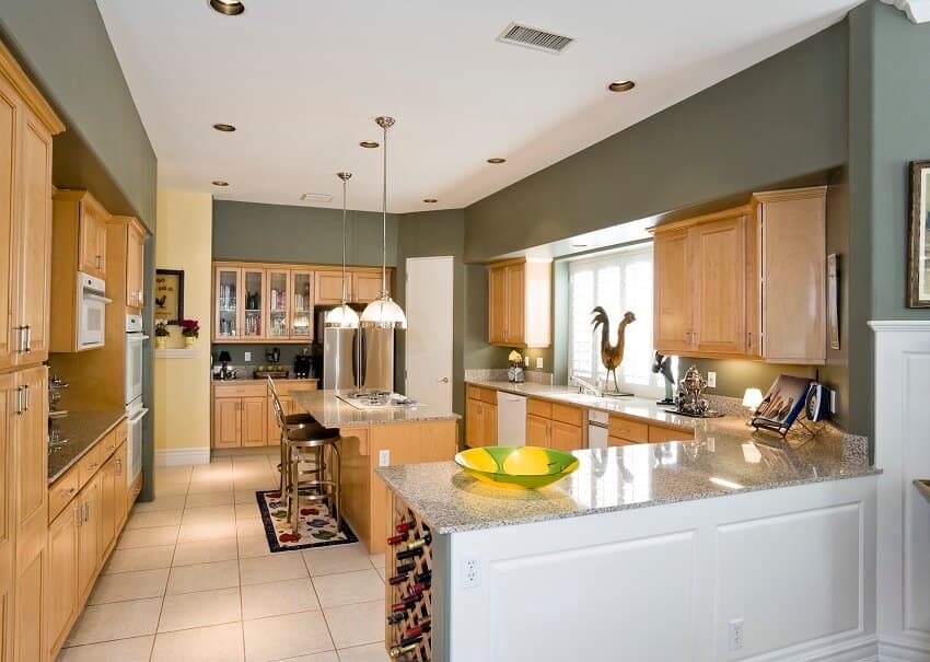 Modern kitchen with stools at the island pendant lights decors on granite veneer countertop and wooden cabinets