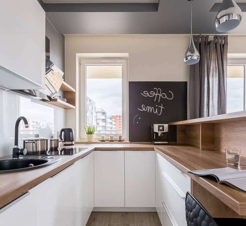 Modern kitchen with wooden worktop white unit and blackboard