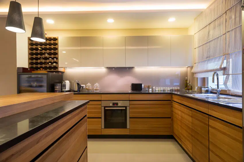 Modern kitchen with zebrawood cabinets black countertop hanging lights sink backsplash