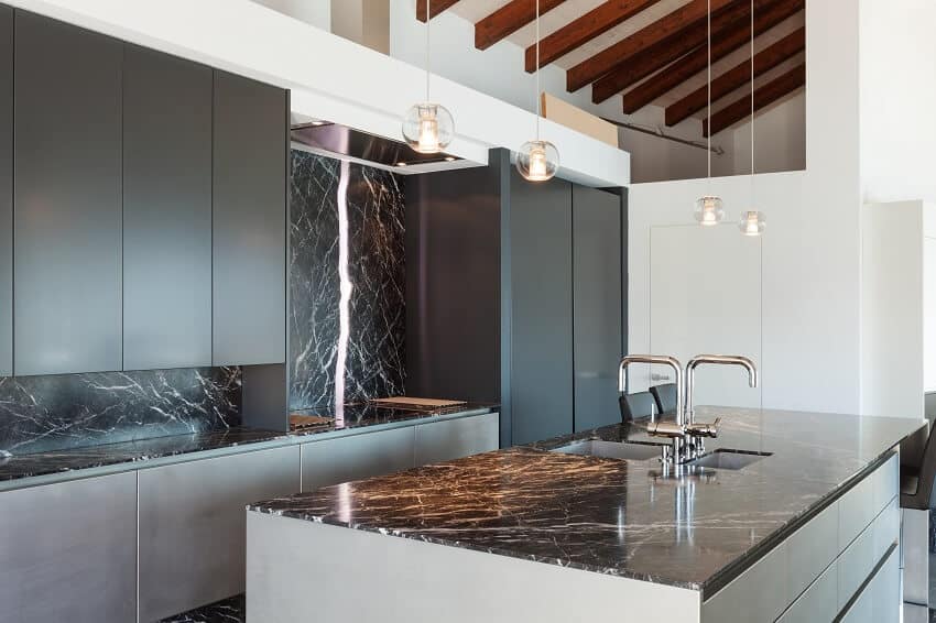Modern loft kitchen with marble countertop pendant lights and black cabinets