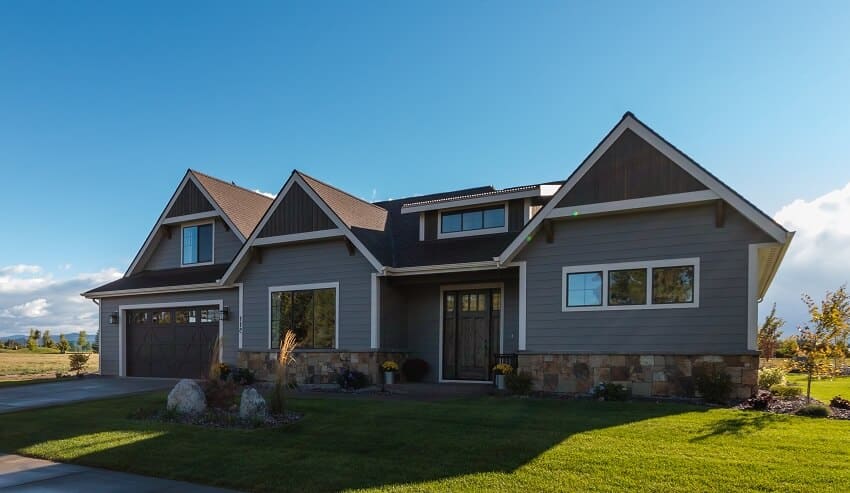 New ranch home with green lawn and wet sidewalk