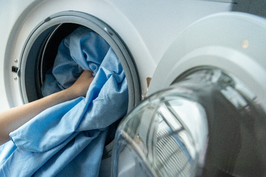 Putting a blue curtain to wash in a washing machine