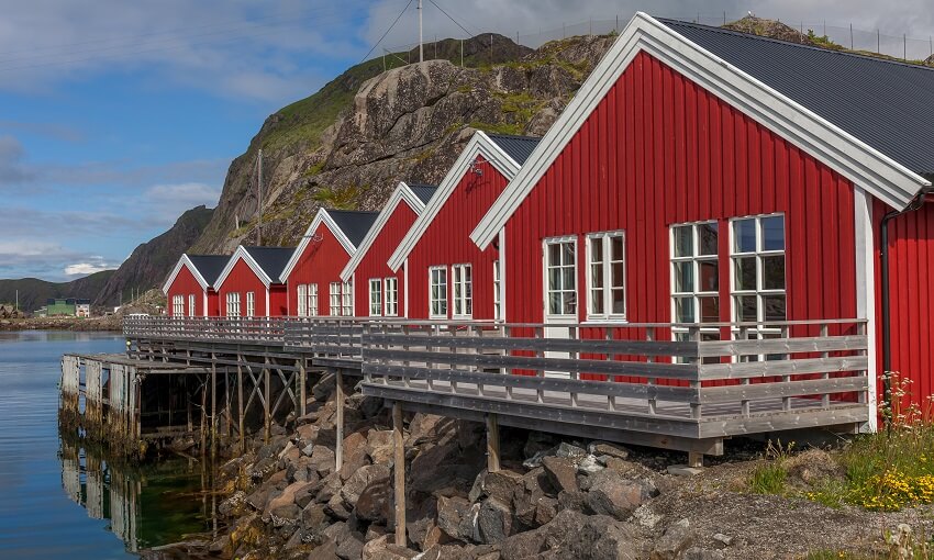 Red rorbu huts with deck and pier foundation on a fjord