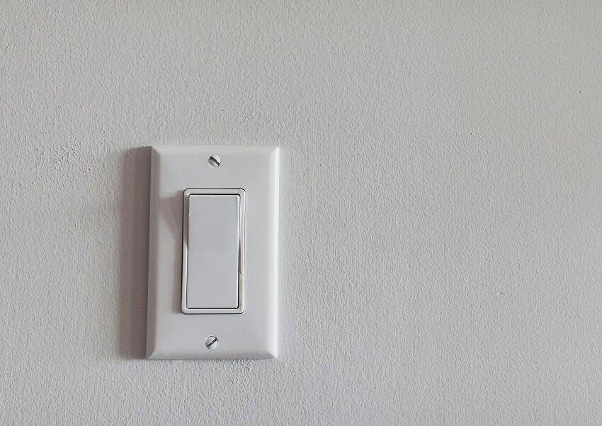 Single light switch on a white wall
