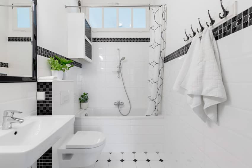 Small bathroom white tiles drop in tub towel mirror sink toilet shower hose