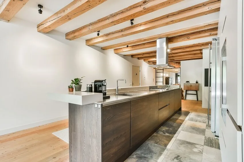 Spacious kitchen with a long island white walls tile & wood floors and beams on the ceiling