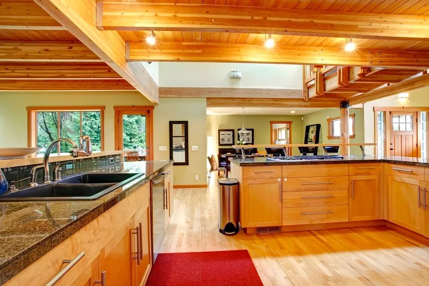 Spacious kitchen with ceiling beams wood floors granite countertops wood cabinets bar stools and view of the dining area