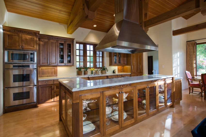 Kitchen with island countertop, stianless steel hood wood cabinets and backsplash