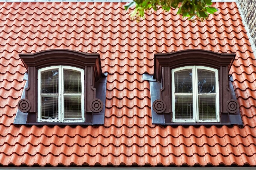 Two attic windows with white frames on the roof of red tiles