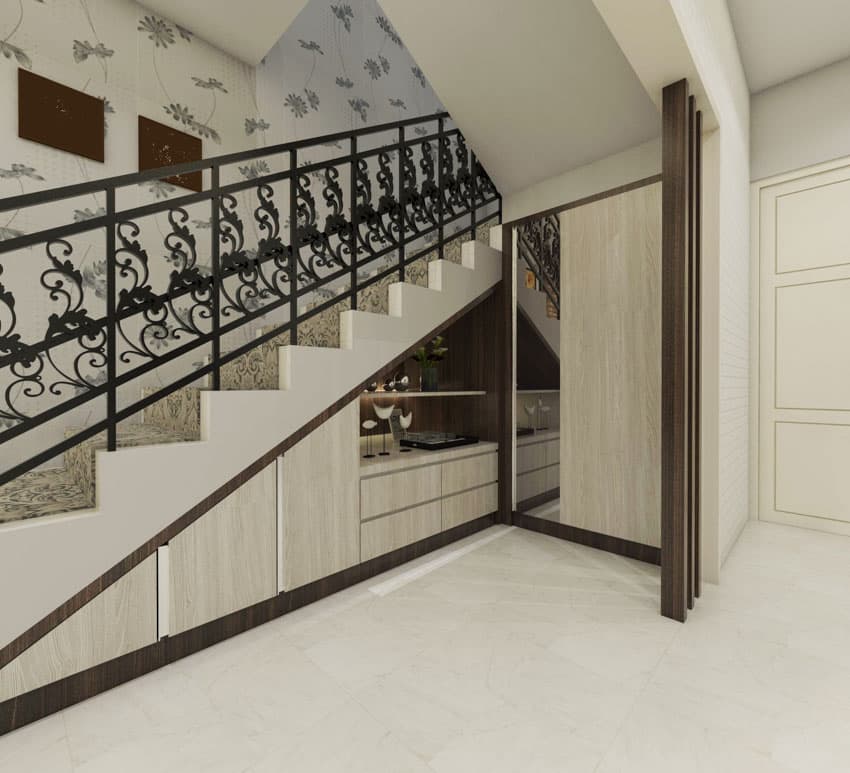 Wallpaper on staircase wall metal railing white floor under stairs storage area mirror