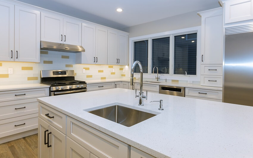 White kitchen with sinks cabinets stainless steel appliance yellow & white backsplash and wood floors