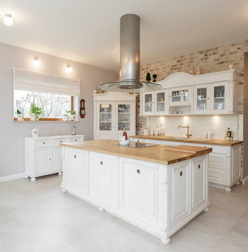 White kitchen with wooden veneer countertop tile flooring and window with plants