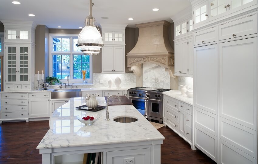 White marble kitchen with hardwood floors stainless steel appliances decors lighting fixrtures and white enamel custom cabinets