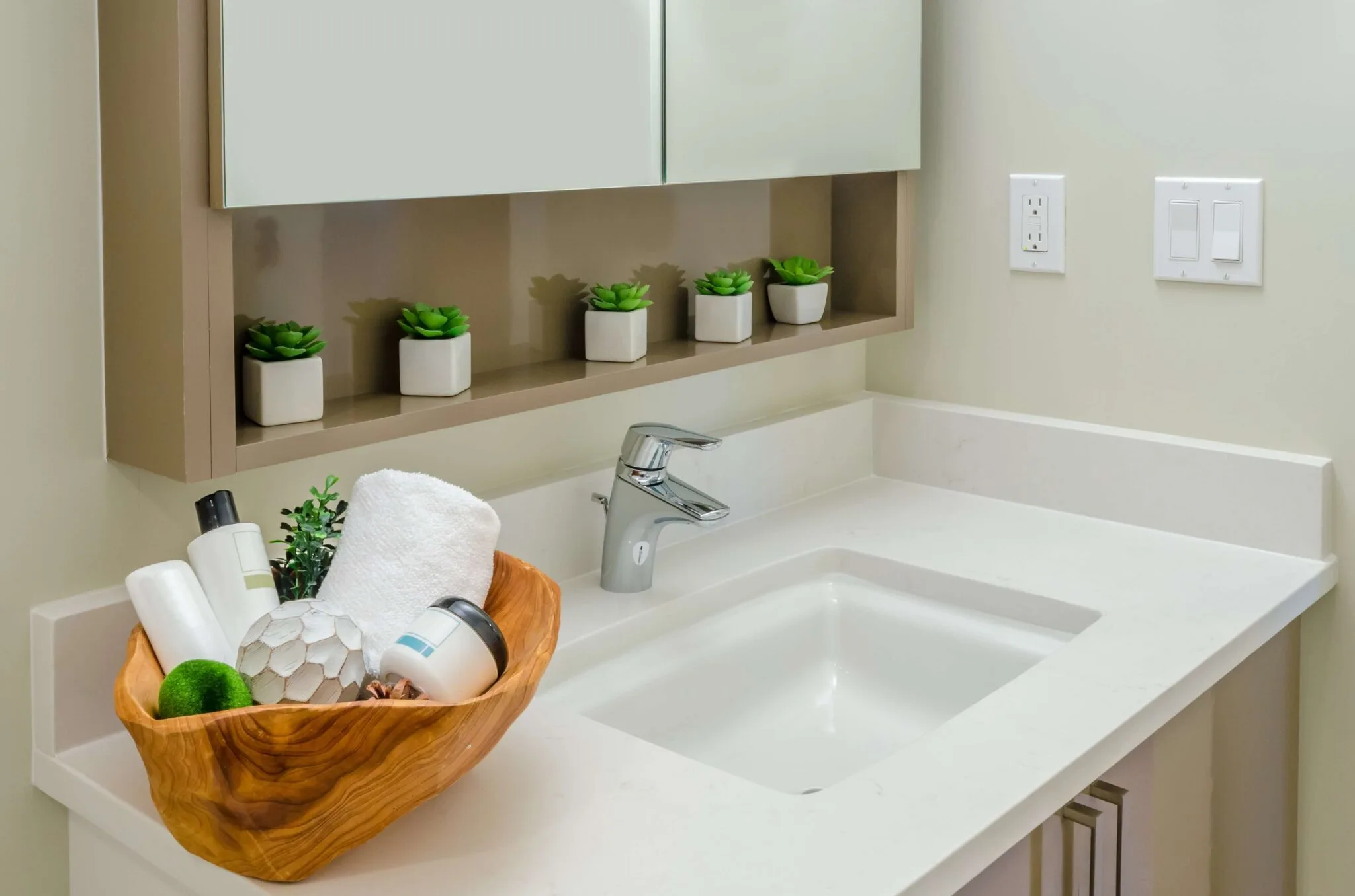 White sink with faucet cabinets succulents switch and wooden bowl with bathroom essentials