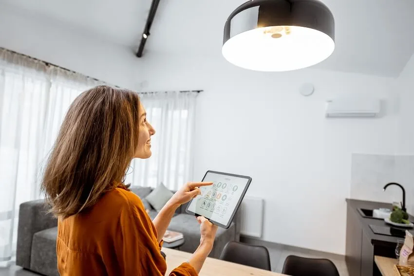 Woman controlling home light with a digital tablet in the living room of a smart home