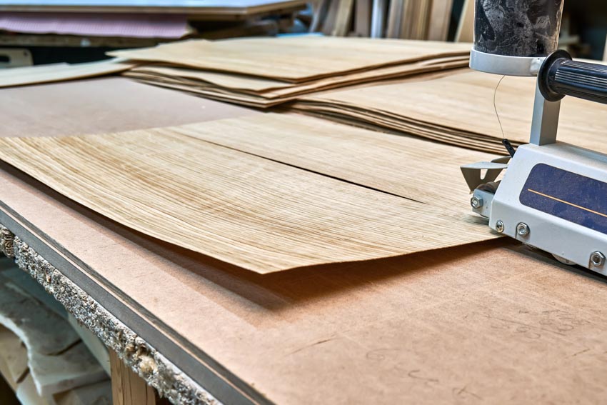 Wood veneer sheets being cut on table