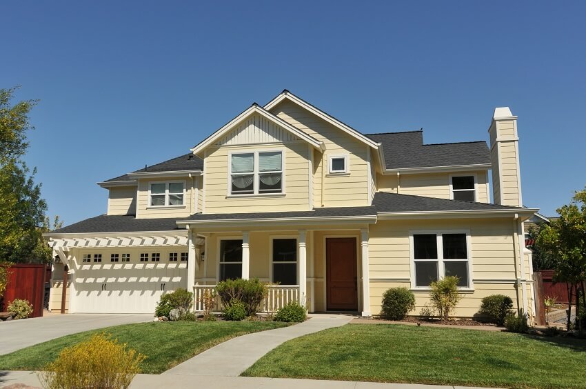 Yellow two story house with a lawn and a short driveway