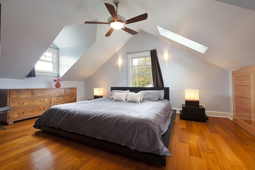 Attic bedroom with wooden floor platform bed modern bedside table ceiling fan skylight