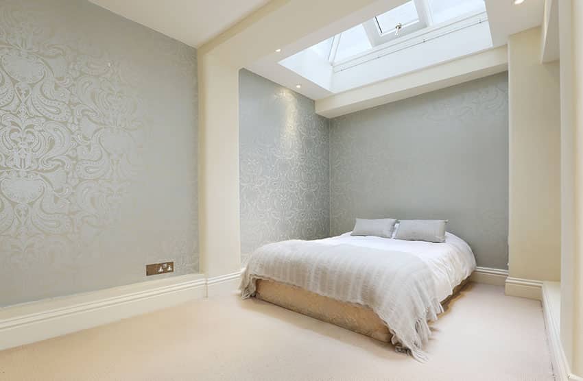 Bedroom with teal wallpaper cream accent paint skylight