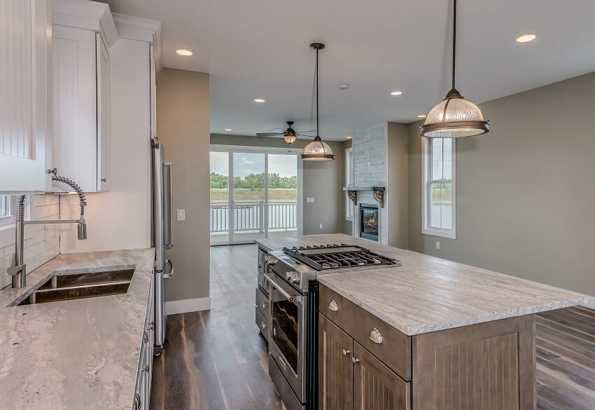 Empty open space kitchen with two hanging lights above island range, grey walls and marble