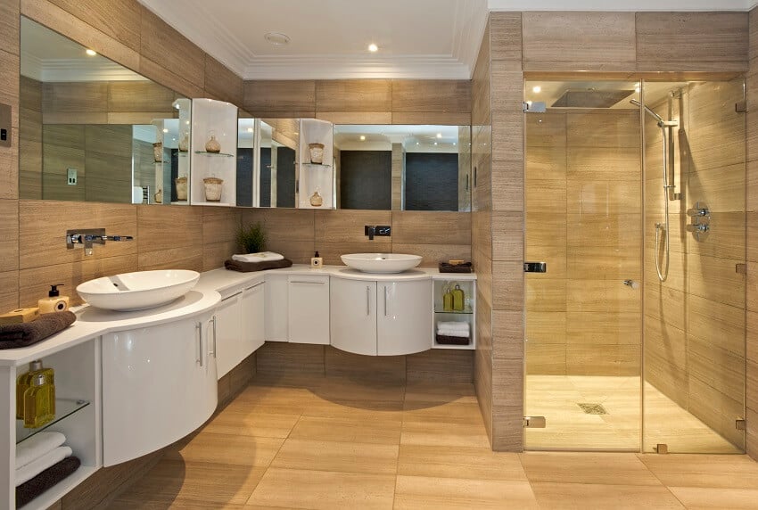 Bathroom suite in a luxury home with a large shower unit curved white cabinets with his and hers basins and fossil marble floor