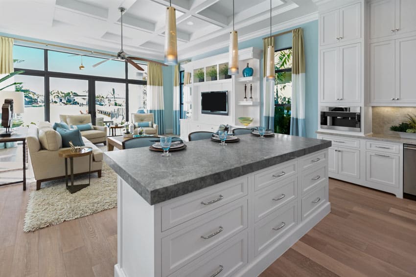 Beautiful kitchen with granite countertop on center island wood flooring ceiling fan coffered ceiling white cabinets drawers glass windows foors chairs