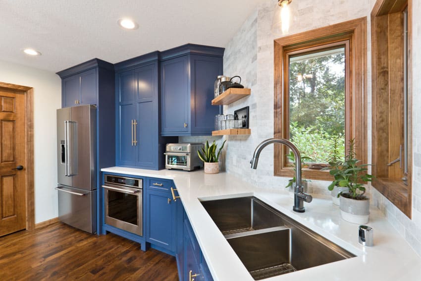 Beautiful kitchen with quartz countertop overlay blue cabinets wood floor sink windows