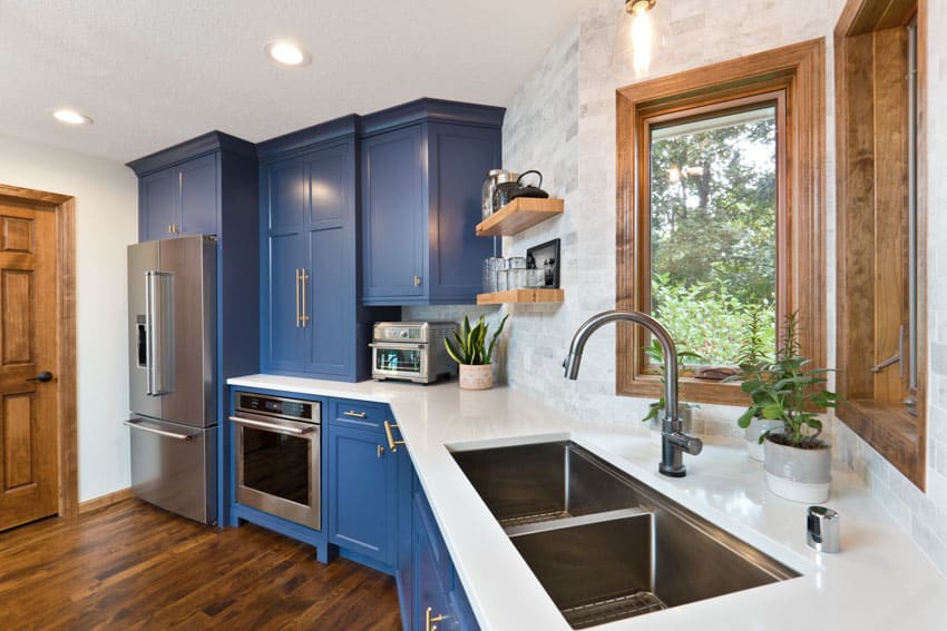 Beautiful kitchen with quartz countertop, blue cabinets, wood floor and corner sink