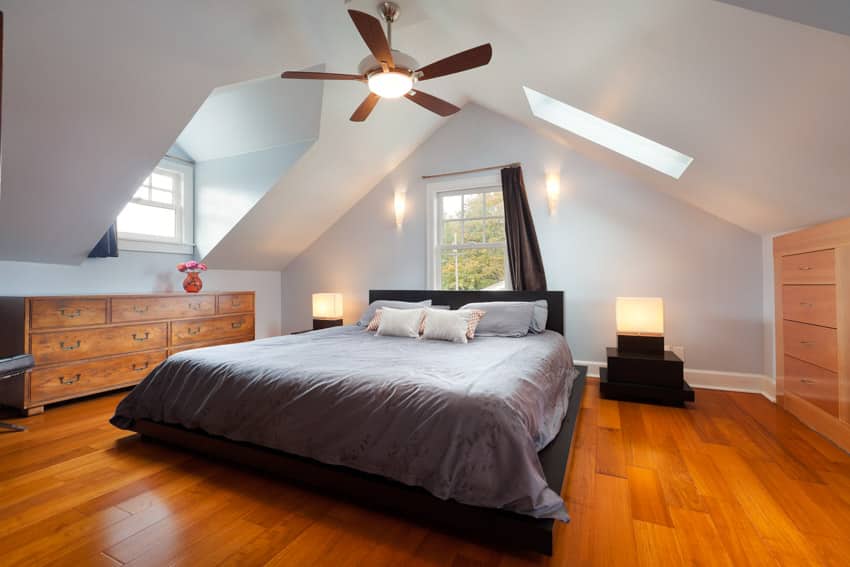 Bedroom with sloped ceiling ceiling fan skylight wood flooring lamp windows