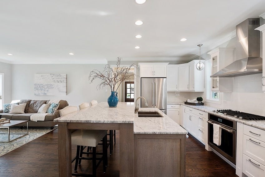 Brown and white open kitchen with marble topped double level island with stools