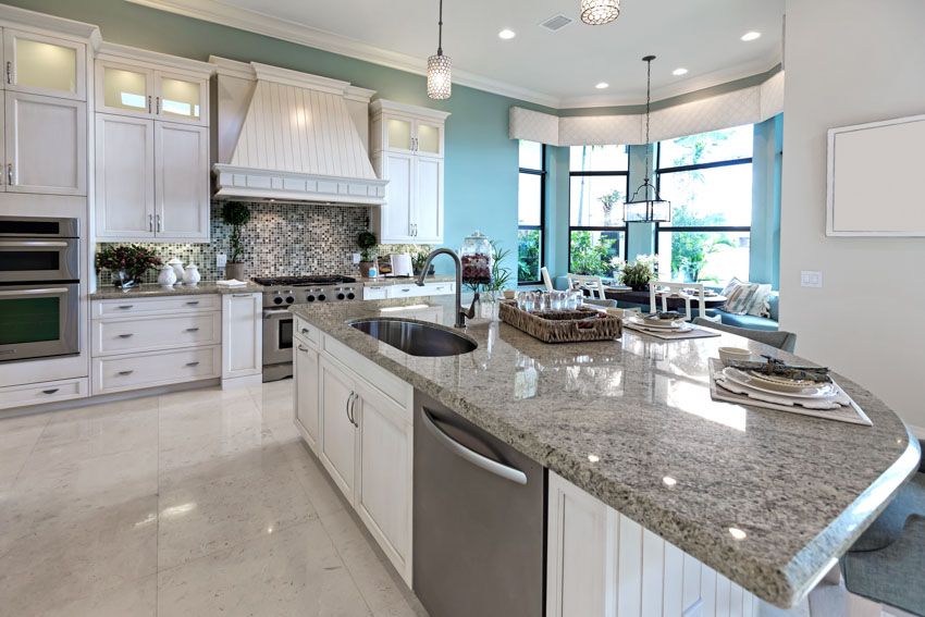 Classic kitchen with dolomite countertop white cabinet drawer center island hood green wall windows tile floor
