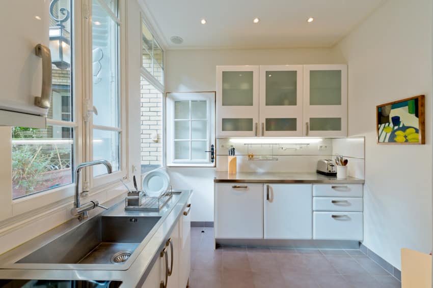 Classic kitchen with pewter countertop windows white drawers and cabinets sink faucet
