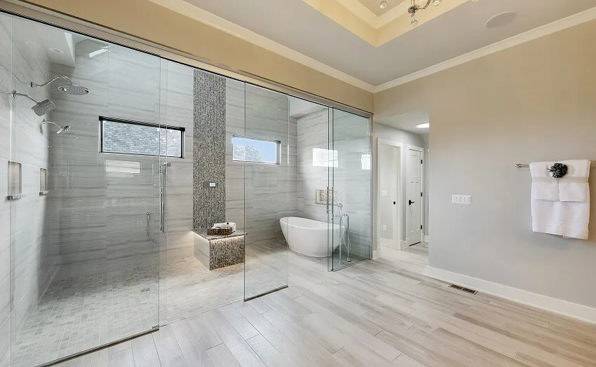 Contemporary bathroom with freestanding tub double shower grey tile wall and mosaic tile bench enclosed in glass