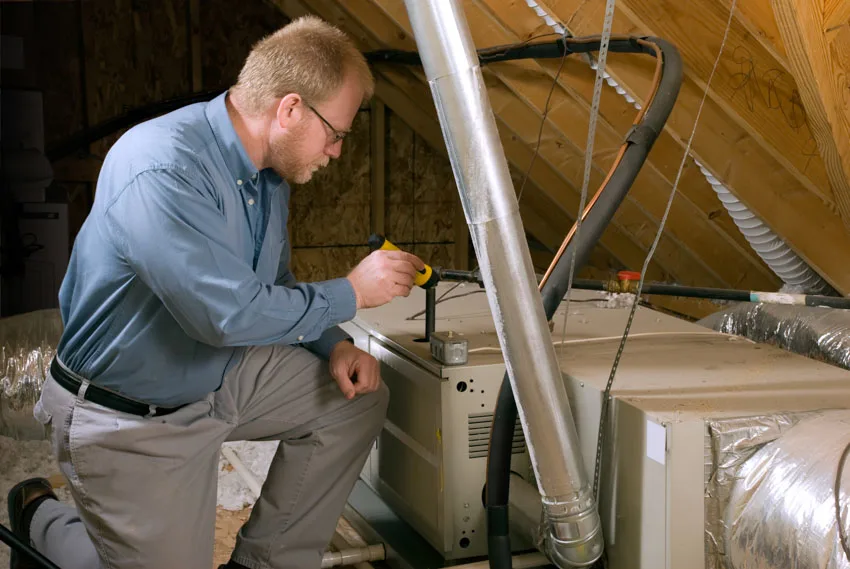 Contractor maintaining house dehumidifier attic