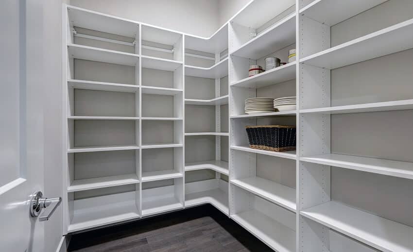 Empty walk-in pantry interior with white shelves and dark wood floor