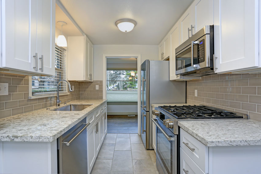 Galley style kitchen backsplash countertops made of oyster shell white cabinets tile floor