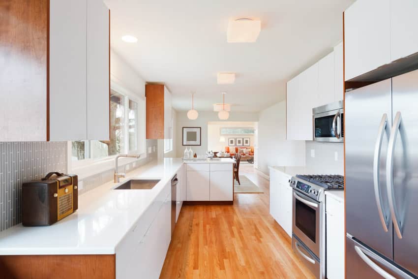 Galley style kitchen nanoglass countertops wood flooring white cabinets windows sink hood stove kitchen