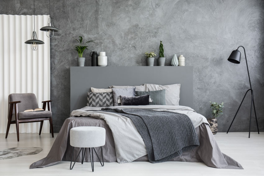 Gray concrete wall bedroom indoor plant headboard floor lamp chair