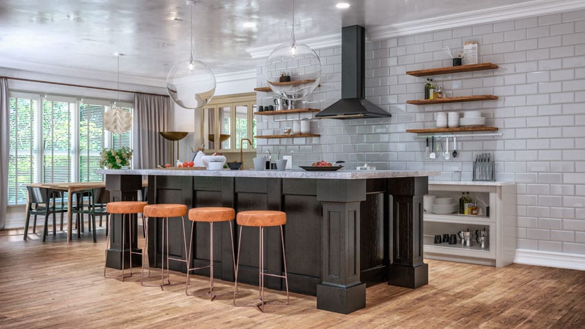 Kitchen space with center island, hanging pendant light, glass subway tile wall backsplash, wood floor, dining area, and windows