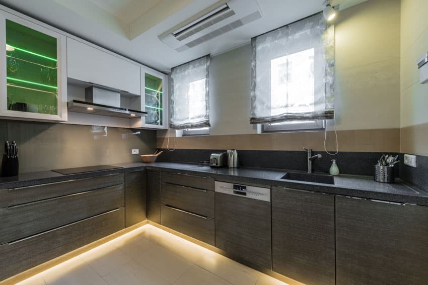 Kitchen with black countertop overlays wood cabinets floor lighting windows sink faucet