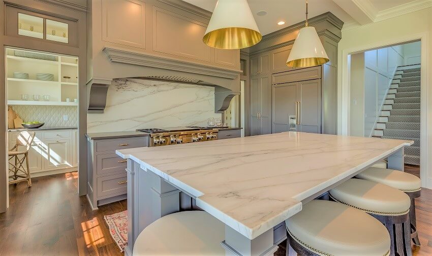 Kitchen with grey cabinetry, hardwood floors, honed surface island 